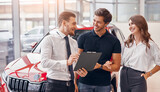Male dealer selling car to couple