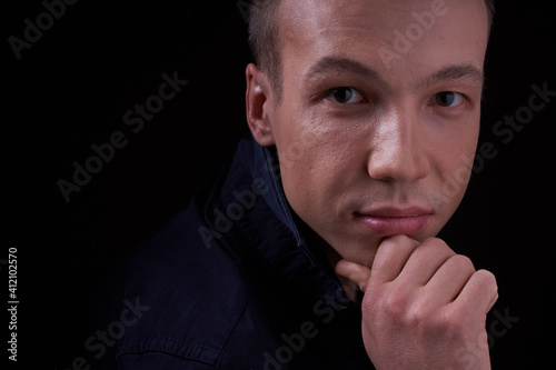 Close up portrait of a beautiful confident young man on a black isolated background in a Studio with copy space, he looks at the camera