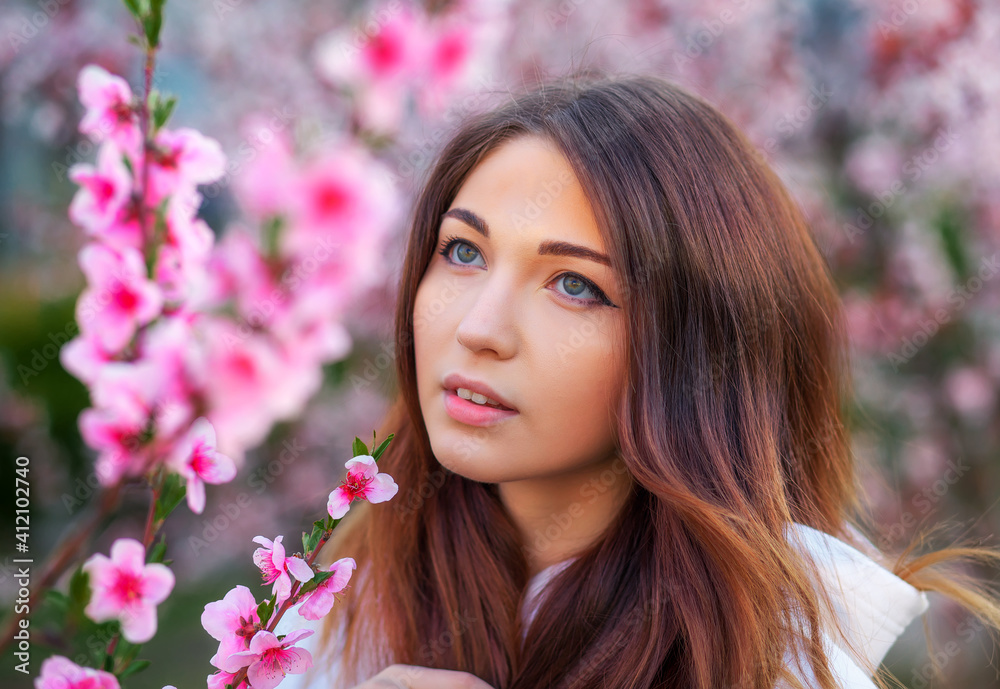 Smiling beautiful girl standing near a peach tree during sunset. Happy face. Spring time. Smiling beautiful girl standing near a peach tree during sunset. Happy face. Spring time.
