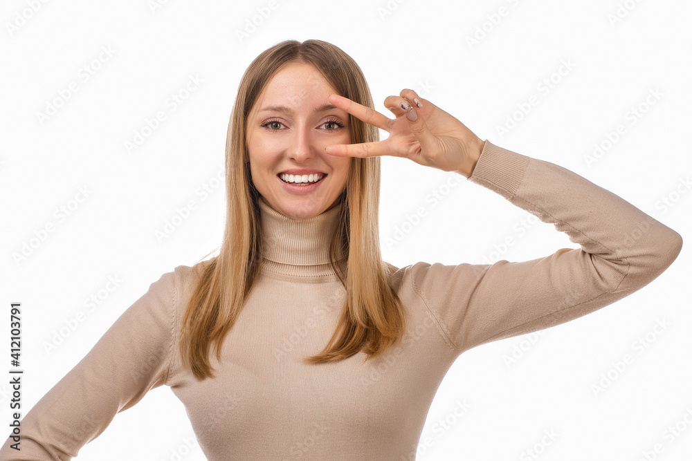 Portrait of optimistic blond girl showing peace sign over eye and smiling, white background. Just be cool about it Portrait of optimistic blond girl showing peace sign over eye and smiling, white background. Just be cool about it