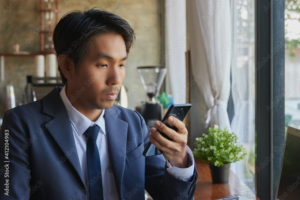 Zoom View Front Right Asian Businessman in Suit and Tie Using Smartphone in Coffee Shop Scene. Asian Businessman Work from Anywhere with Technology Zoom View Front Right Asian Businessman in Suit and Tie Using Smartphone in Coffee Shop Scene. Asian Businessman Work from Anywhere with Technology