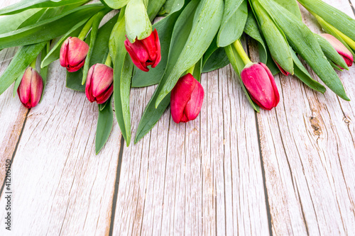 Beautiful flat lay with red tulips flowers on a light grey wooden texture. Colorful Card for Mothers Day, Birthday, International Women's Day March 8. Selective focus.