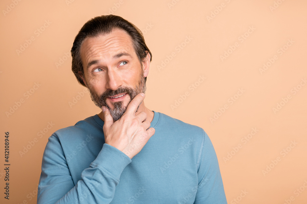 Photo of minded mature guy finger chin look up empty space wear blue sweater isolated beige color background Photo of minded mature guy finger chin look up empty space wear blue sweater isolated beige color background
