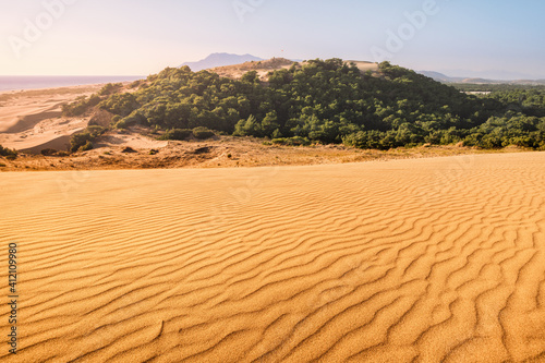 Idyllic landscape with golden sand dunes of Patara illuminated by the rays of the setting sun and the blue sea on the horizon. Travel destinations in Turkey