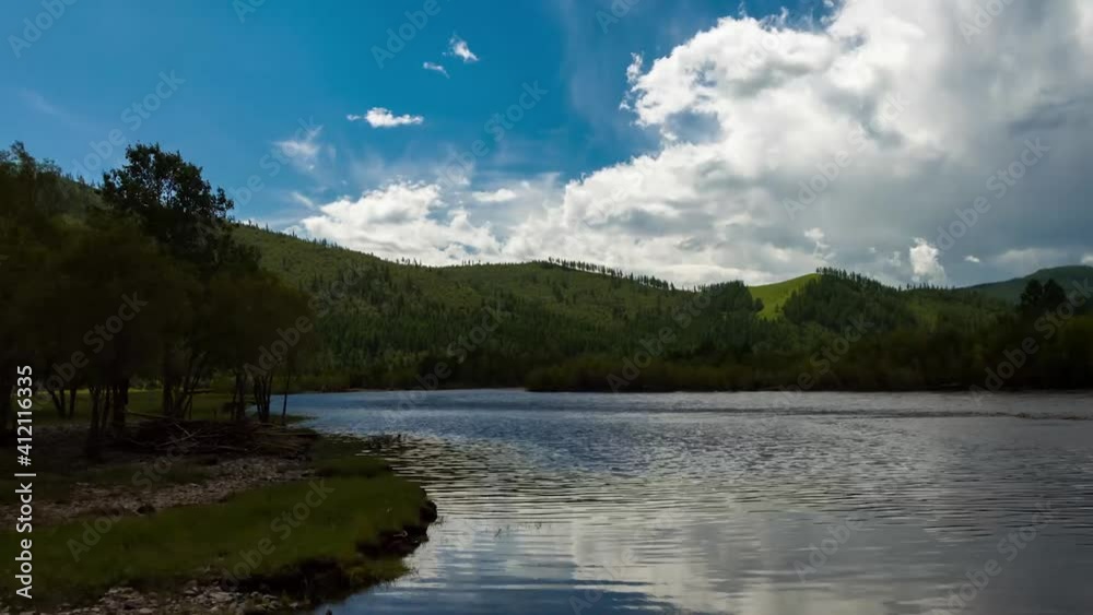 Timelapse in the blue sky, clouds float over the mountains and the river with trees Timelapse in the blue sky, clouds float over the mountains and the river with trees