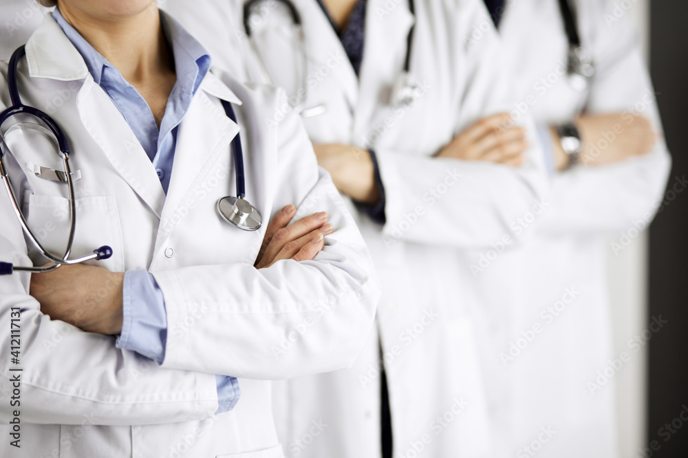 Group of modern doctors standing as a team with arms crossed in hospital office and ready to help patients. Medical help, insurance in health care, best disease treatment and medicine concept Group of modern doctors standing as a team with arms crossed in hospital office and ready to help patients. Medical help, insurance in health care, best disease treatment and medicine concept