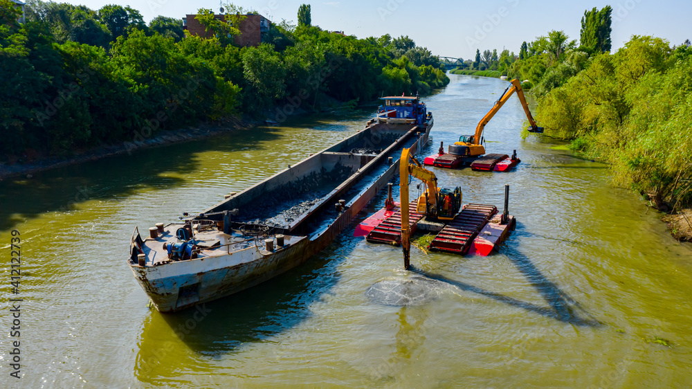Fototapeta premium Aerial view of river, canal is being dredged by excavators