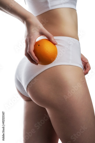 Closeup view of slim woman in underwear with orange on white background.