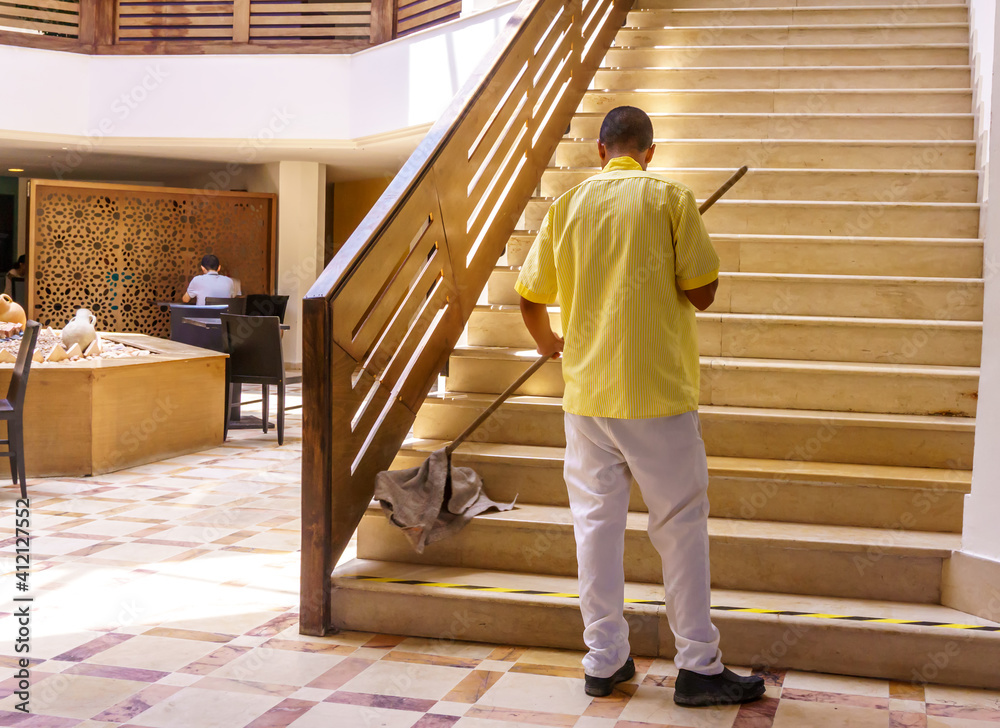 A hotel employee cleans the stairs with a mop. Wet cleaning of premises.