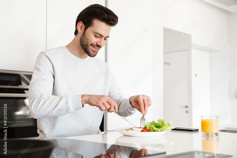Happy handsome man smiling while having breakfast at home kitchen Happy handsome man smiling while having breakfast at home kitchen