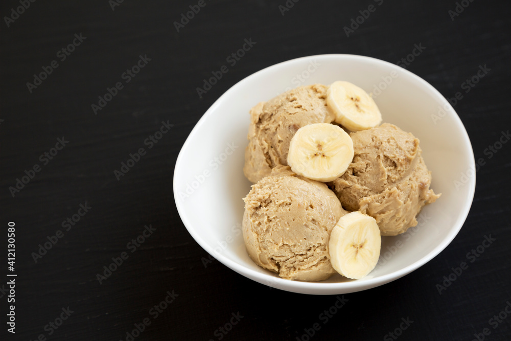 Homemade Peanut Butter Banana Ice Cream in a Bowl on a black surface, side view. Copy space.