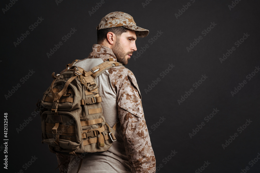 Confident masculine military man in uniform posing with backpack Confident masculine military man in uniform posing with backpack