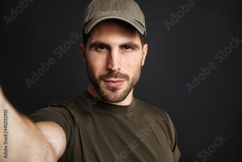 Pleased military man taking selfie photo and looking at camera
