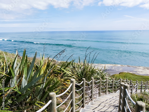 Beautiful lookout over the ocean with a walkway to the beach and green grass. New Zealand west coast, south island. photo