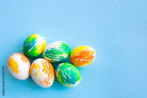 Top view of multicolored Easter eggs on a blue background. Happy Easter card. Dyed Easter eggs. Copy space for your text. Flat lay style. Top view. 