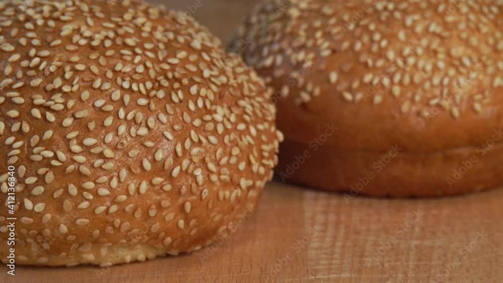 Camera movement on fresh hot bun with sesame seeds on wooden cutting board. Hamburger sandwich bun. Food bread breakfast concept Camera movement on fresh hot bun with sesame seeds on wooden cutting board. Hamburger sandwich bun. Food bread breakfast concept