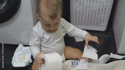 Baby boy hand holding roll and tearing white toilet paper. photo