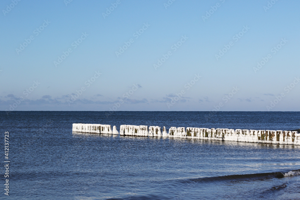 beach at winter with breakwater in ice