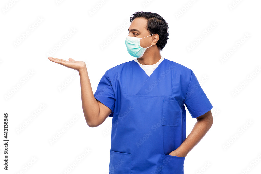 healthcare, profession and medicine concept - indian doctor or male nurse in blue uniform and face protective medical mask showing something imaginary over white background