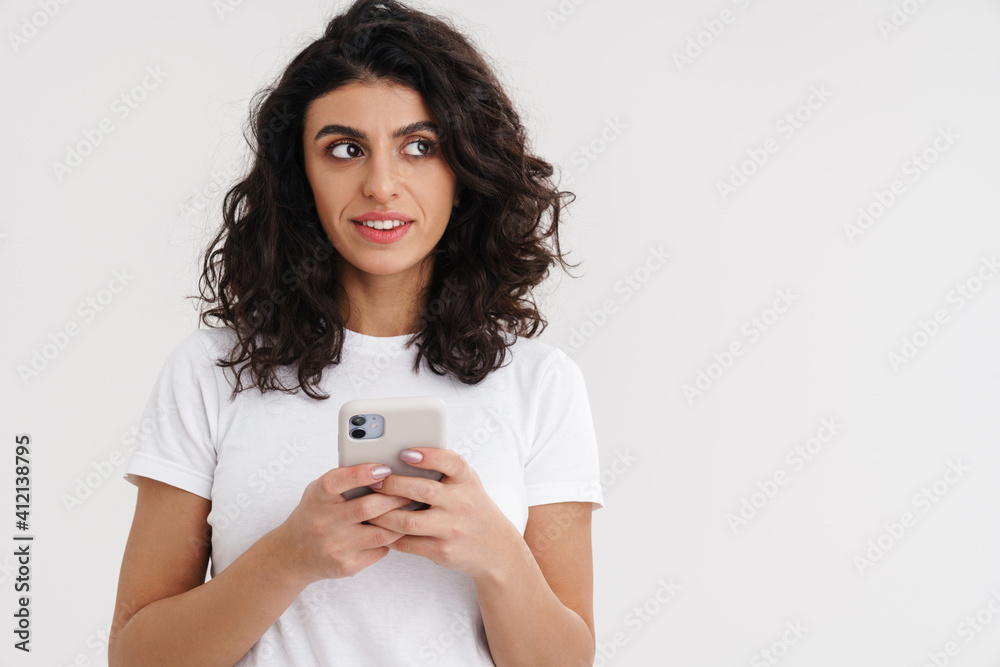 Pleased brunette girl looking aside while using mobile phone Pleased brunette girl looking aside while using mobile phone
