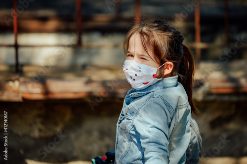 Little girl wearing a mask playing outside during the pandemic year of 2021