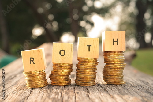 Close up of stacking coins and wooden blocks with text ROTH. Business and finance concept