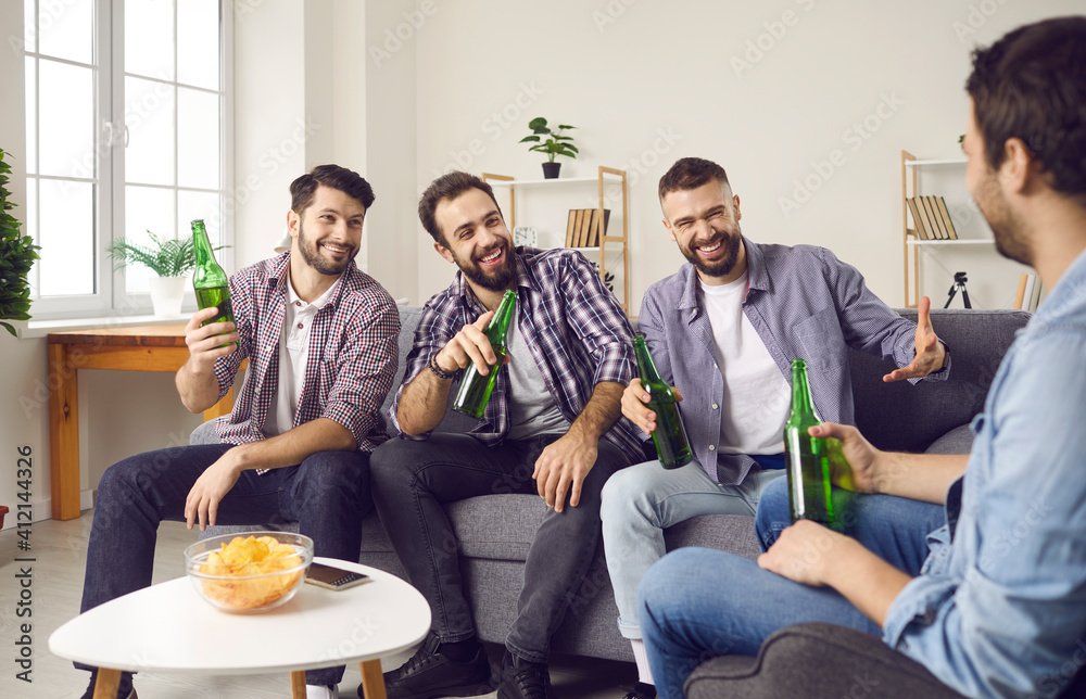 Group of happy male friends having fun on the weekend. Young men sitting on  sofa at
