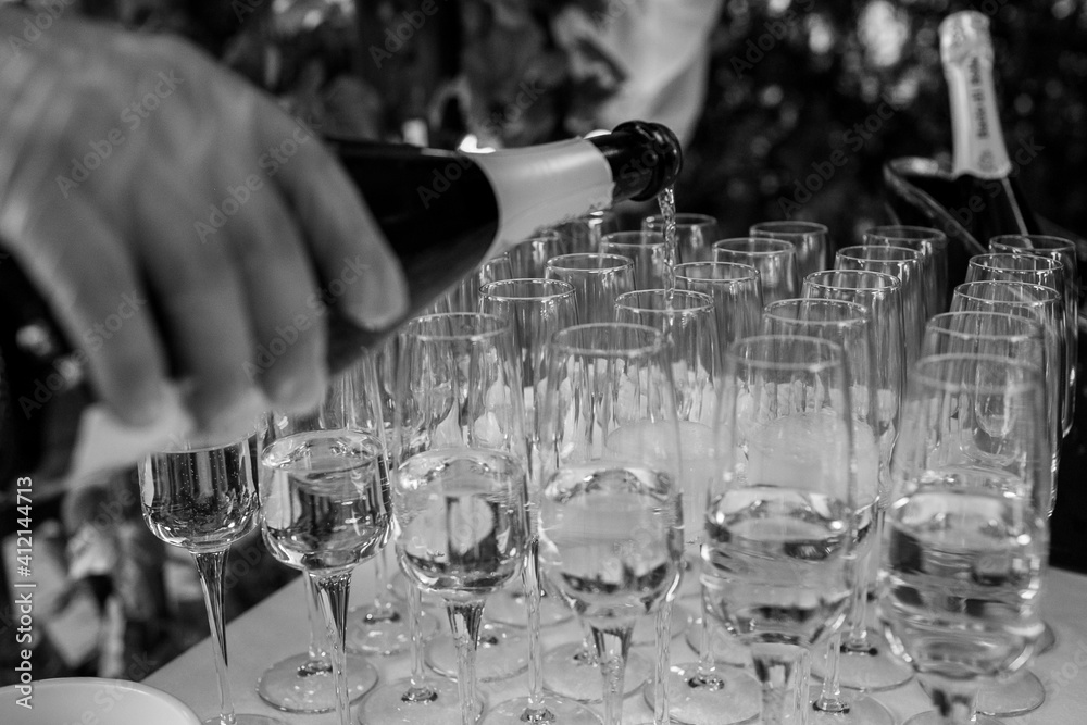 wedding reception. waiter pouring sparkling wine in glasses. black and white. High quality photo