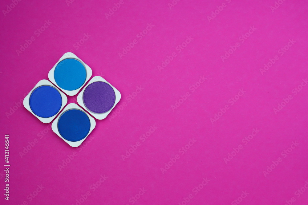 Palette of blue and lilac shades of watercolor paints on a bright pink background Palette of blue and lilac shades of watercolor paints on a bright pink background