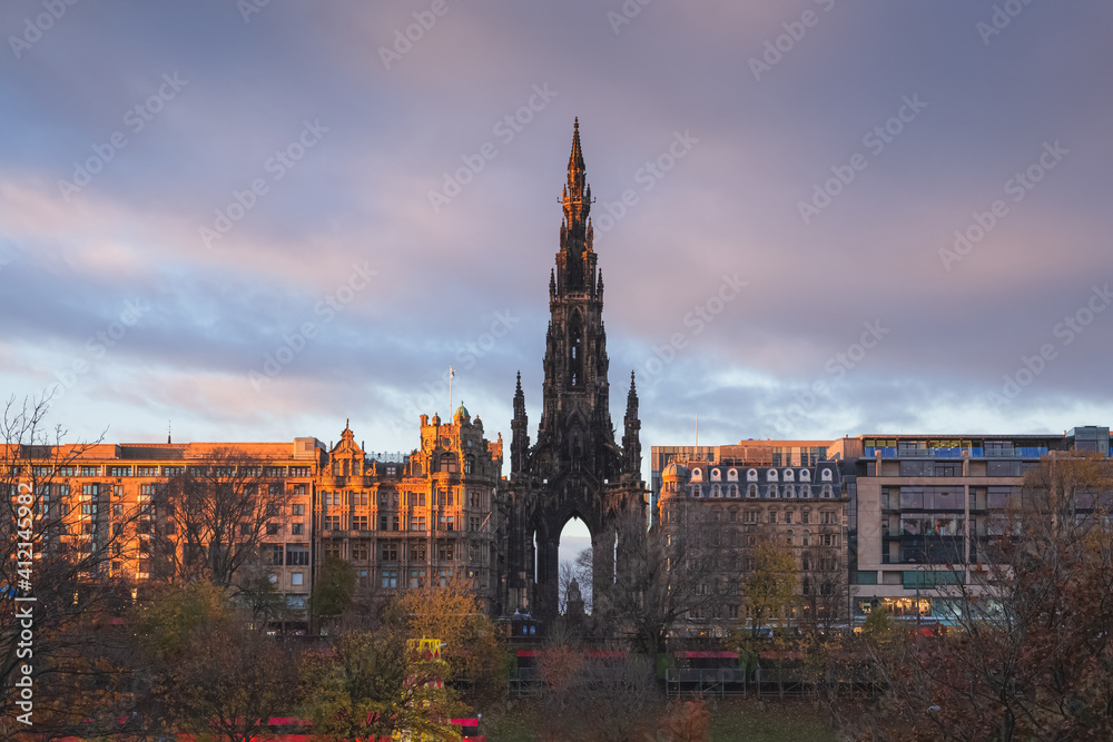 View of the Sir Walter Scott Monument and new town cityscape skyline from Old Town Edinburgh overlooking Princes Street Gardens with colourful clouds at sunset or sunrise.