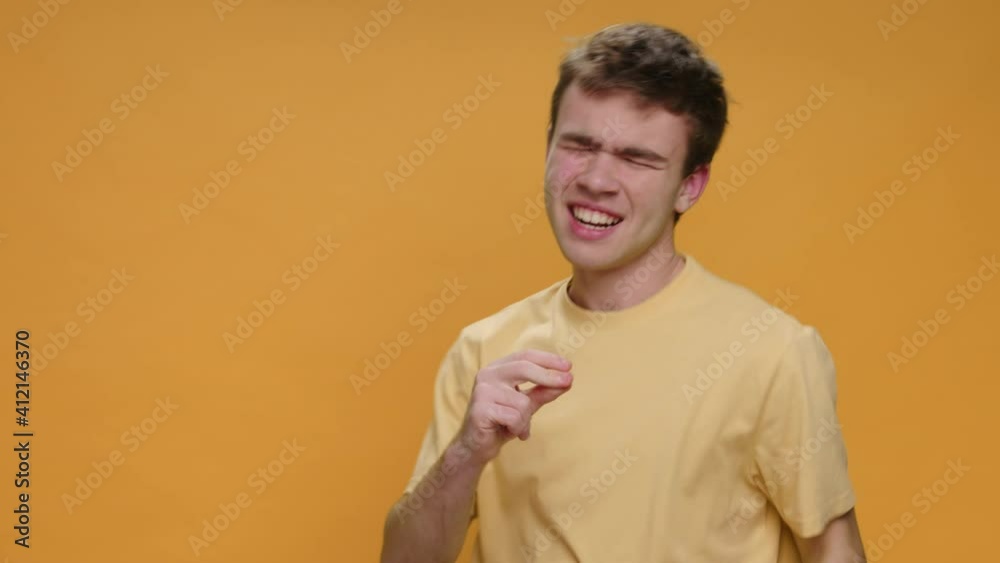 Dancing Happy Young Man Teen Sings to Music Track Waving his Arms Rhythmically Slow Motion in Yellow T-shirt on Yellow Background. Monotone. Positive Emotions. Humor