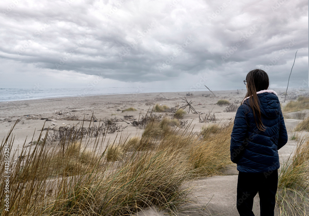 Landscape of a winter beach with girl looking to the horizon 