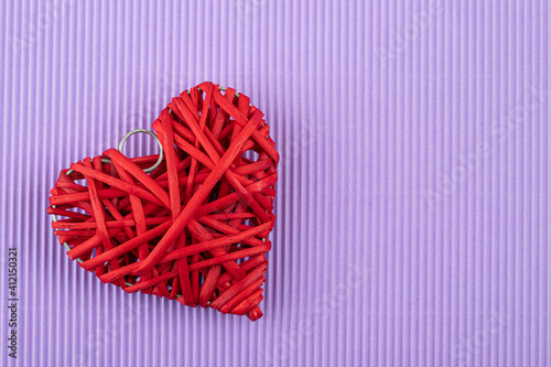red rattan heart wood close up on textured violet paper background, saint valentines concept