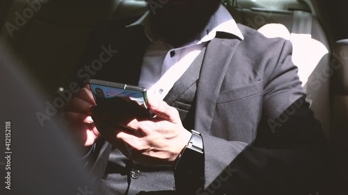Hindu businessman in a suit and glasses uses the phone in the car. close-up