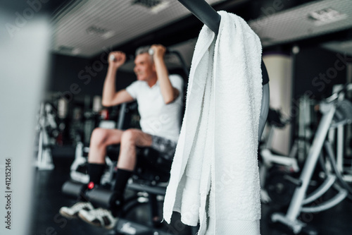 In focus, a towel on the gym in the gym, in the background of a blurred man performing an exercise