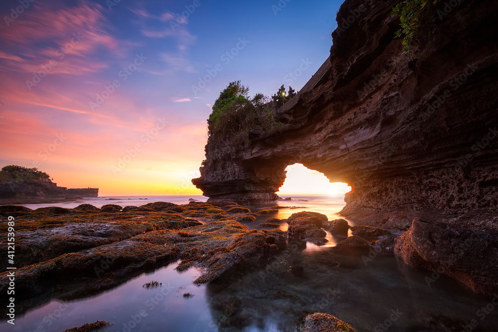 Sunset at Batu Bolong temple and Tanah Lot, Tabanan, Bali. beautiful color with the coral reef in low tide.