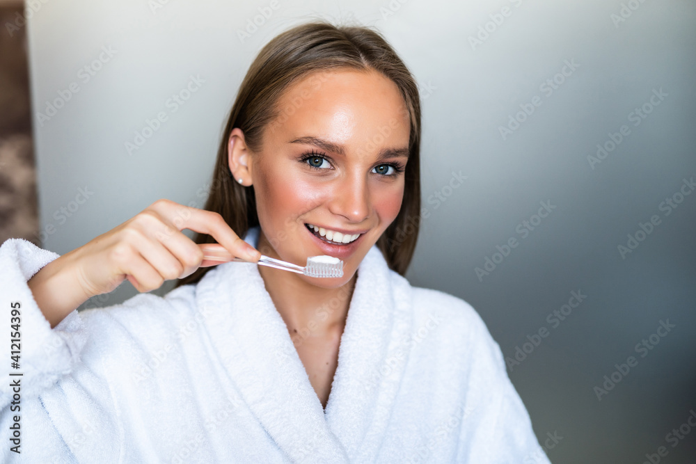 Portrait of young woman with a smile brushing her teeth in bathroom Portrait of young woman with a smile brushing her teeth in bathroom