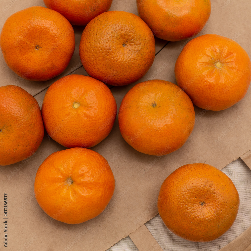 Ripe tangerines, close-up. Several fruits lie on an eco-friendly paper bag and napkin. Top view Ripe tangerines, close-up. Several fruits lie on an eco-friendly paper bag and napkin. Top view
