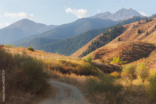 A dirt road and scenic landscape in Kolsai Lakes National Park, located on the north slope of the Tian Shan Mountains in southeast Kazakhstan. photo