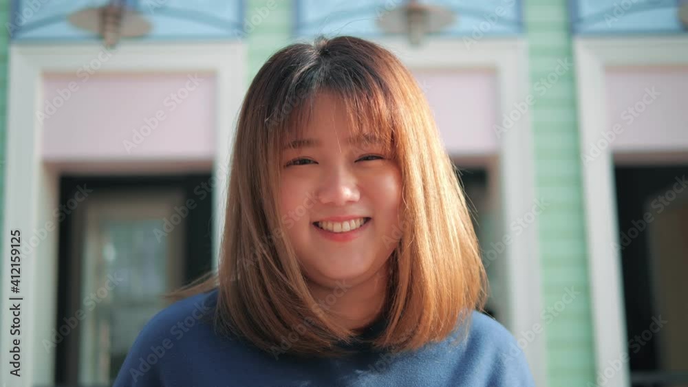 Portrait of young pretty asian woman plump smiling and looking at camera outdoors. Front view. Portrait of young pretty asian woman plump smiling and looking at camera outdoors. Front view.