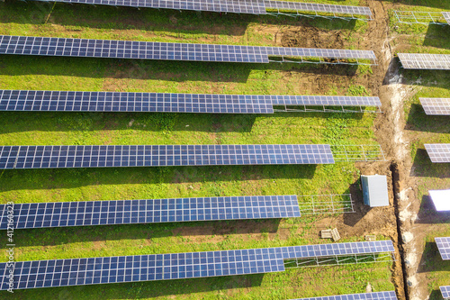 Aerial view of solar power plant under construction on green field. Assembling of electric panels for producing clean ecologic energy.