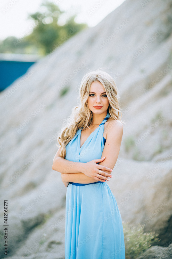 blonde girl in a light blue dress  in a granite quarry