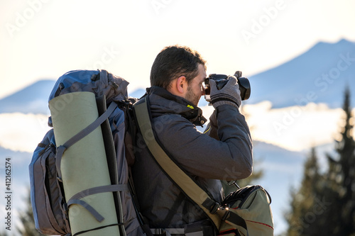 Photographer with hiking backpack taking pictures of nature with digital photo camera.