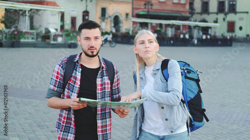 Young couple of tourists with map walking and looking for new historical place in city center. They walking and finding something interesting.