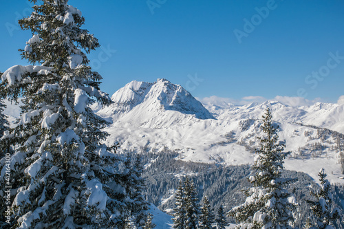  The Austrian Alps in winter near Kitzbuhel. Behind the snow covered fir trees the fog rises revealing the magnificent mountain peaks.