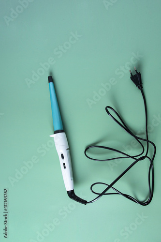 Eco-friendly ceramic curling iron  on green background