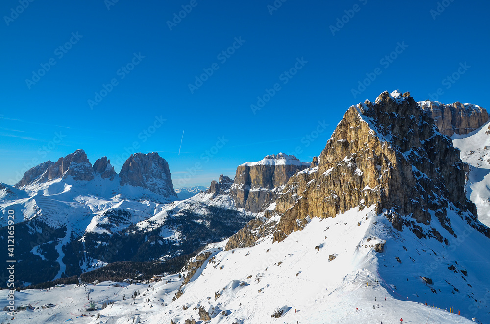  Picturesque cliffs of the Italian Dolomites, surrounded by a pine forest. View from the ski slope of the Village of Sellaronda.