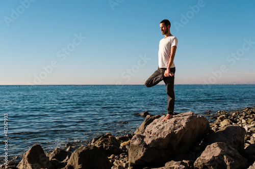 Attractive young man practicing yoga meditation and breathwork outdoors by the sea