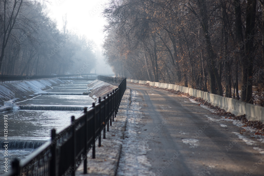 Winter embankment of the river in the fog, park, forest, trees
