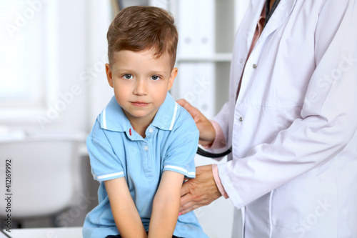 Happy little boy having fun while is being examine by doctor with stethoscope